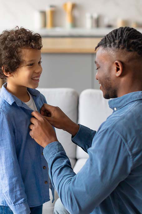 Father helping child button shirt