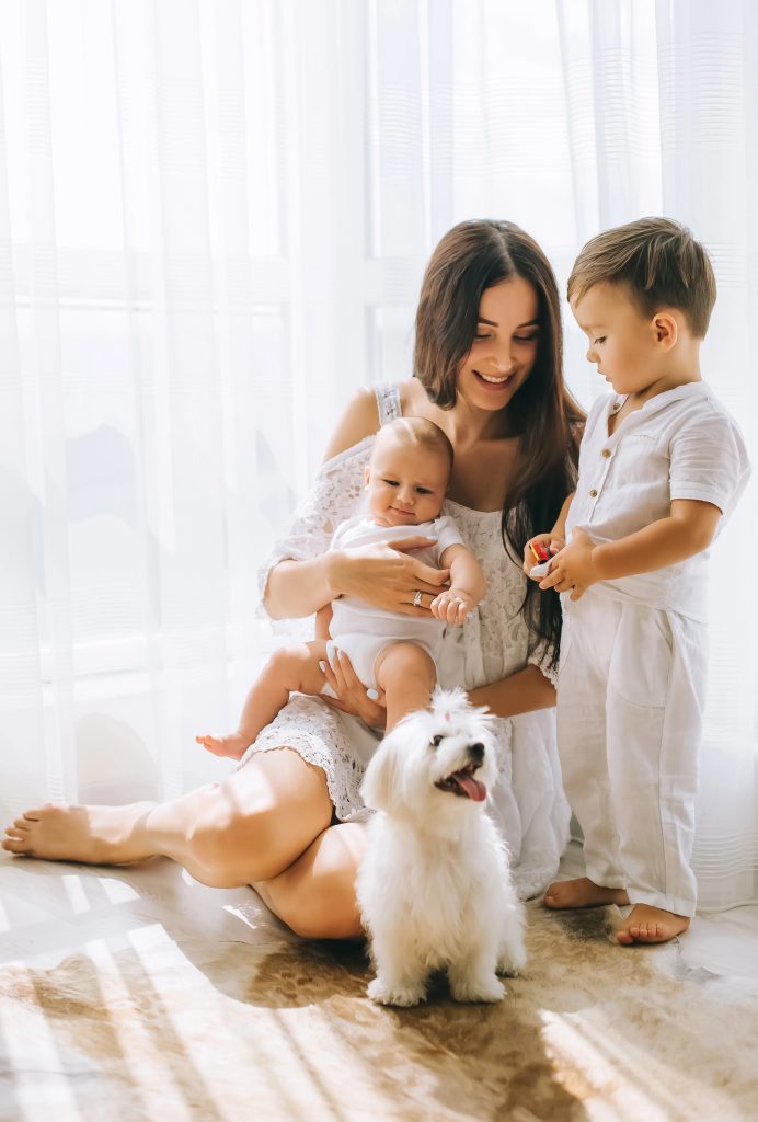 Mother holding baby with young child and dog