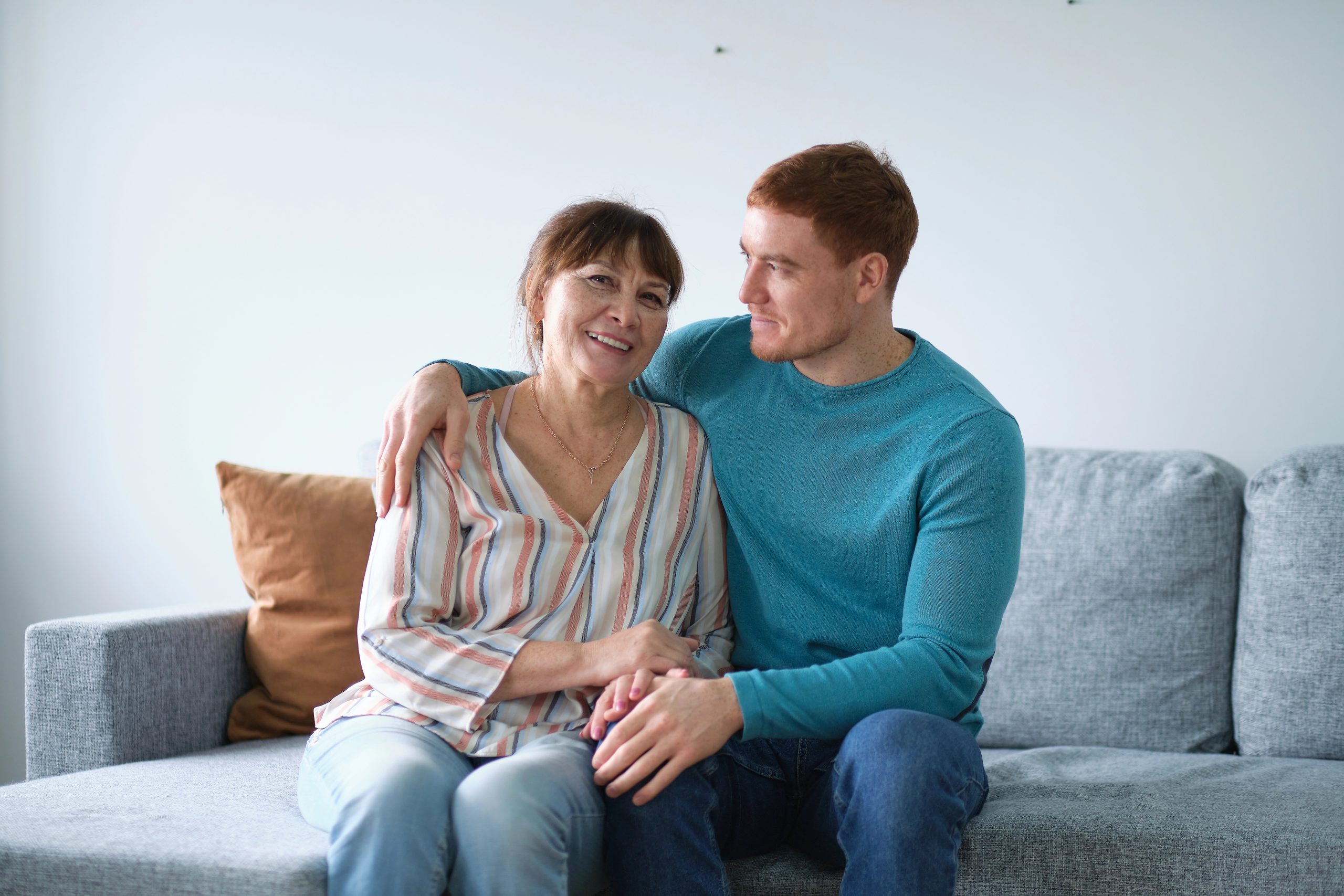 Adult son sitting with mother on couch at home